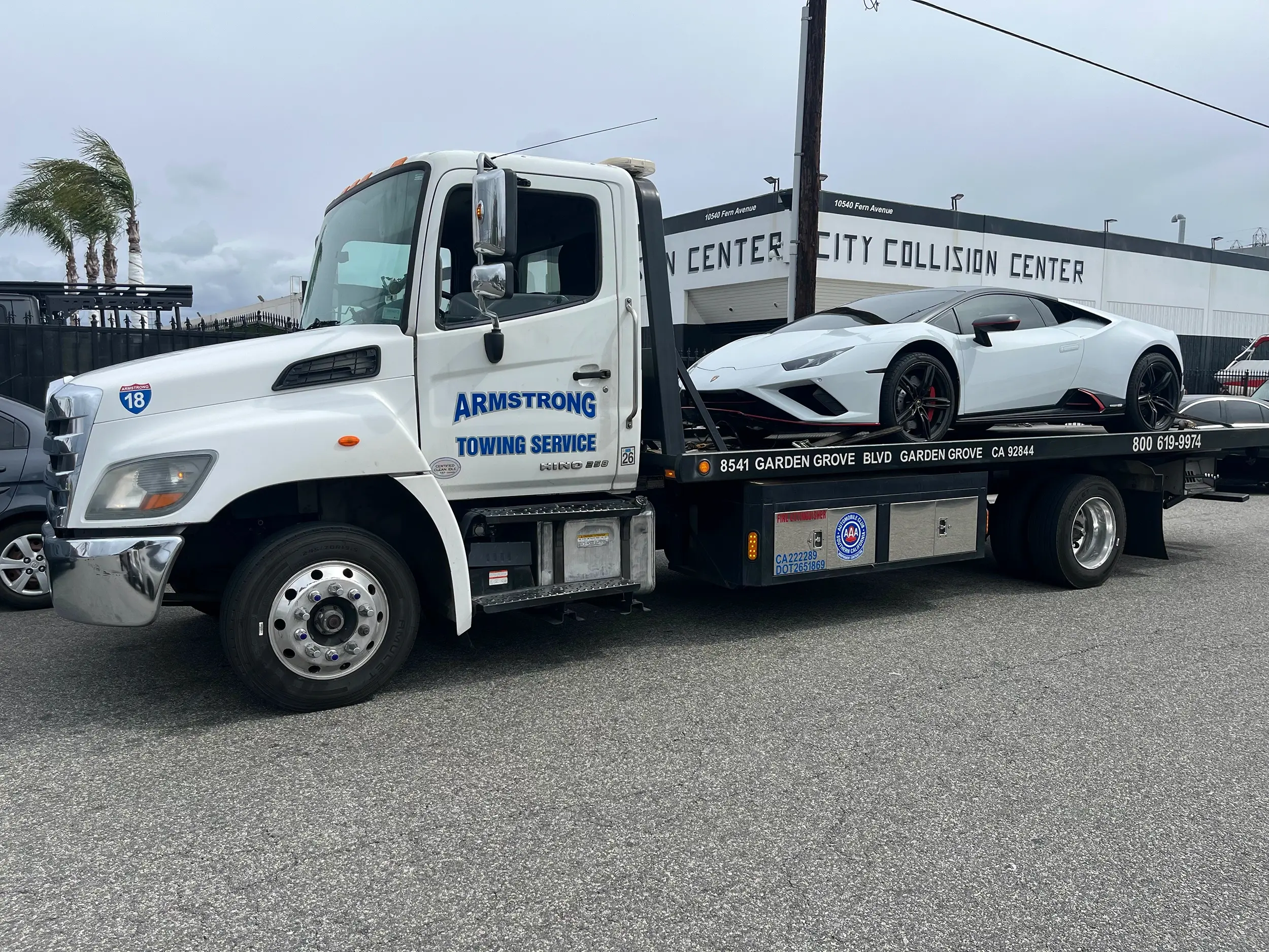 Sedan being winched onto flatbed in parking lot